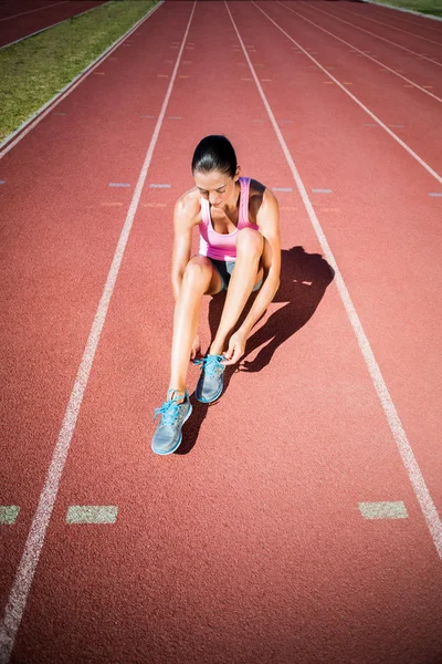 Atleta feminina amarrando tênis de corrida — Fotografia de Stock