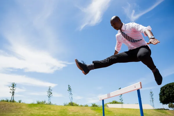 Empresario saltando obstáculo mientras corre — Foto de Stock