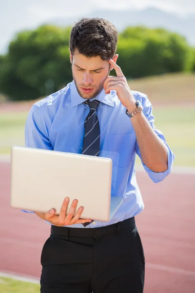 Empresário usando laptop na pista de corrida — Fotografia de Stock