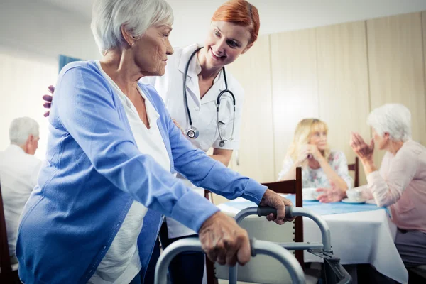 Verpleegkundige een senior die met behulp van een wandelaar bijstaan — Stockfoto