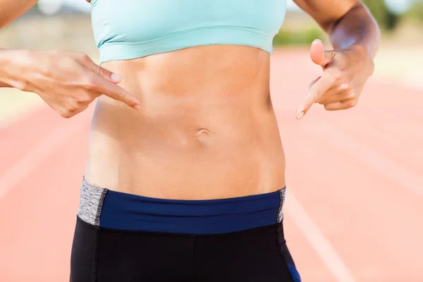 Atleta feminina apontando em sua barriga — Fotografia de Stock