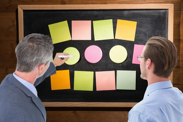 Composite image of businessman is writing on a board — Stock Photo, Image