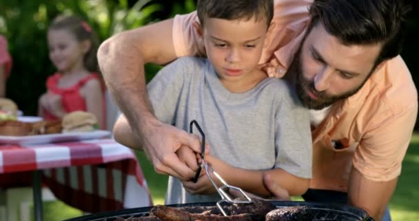 Padre está enseñando a su hijo a hacer una barbacoa — Vídeo de stock