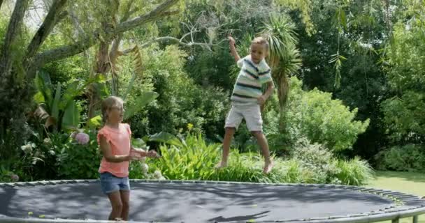 Brother and sister jumping on trampoline — Stock Video