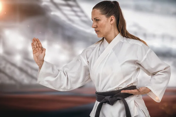 Imagen compuesta de luchadora realizando postura de karate — Foto de Stock