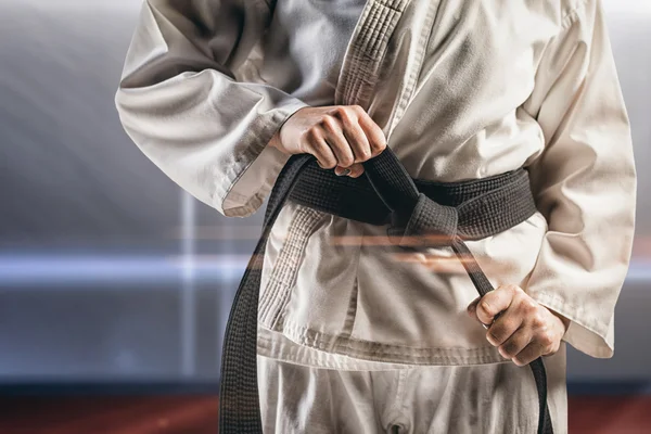 Composite image of fighter tightening karate belt — Stock Photo, Image