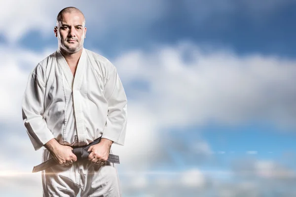 Composietbeeld van fighter aanscherping van karate riem — Stockfoto