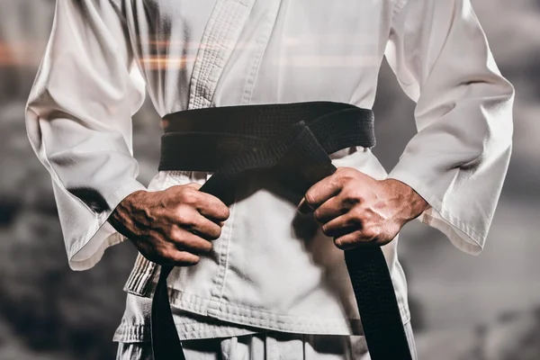 Composietbeeld van fighter aanscherping van karate riem — Stockfoto