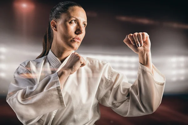 Imagen compuesta de luchadora realizando postura de karate — Foto de Stock