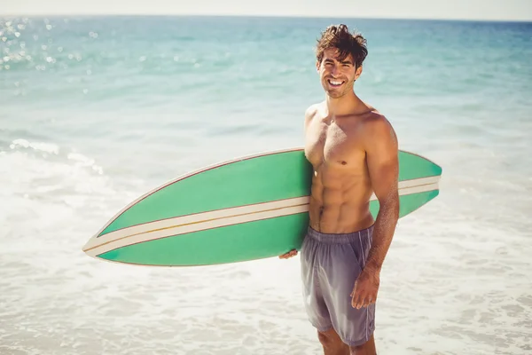 Man anläggningen surfbräda på stranden — Stockfoto