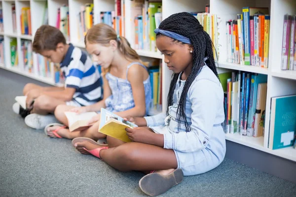 Los niños de la escuela en el suelo en la biblioteca — Foto de Stock