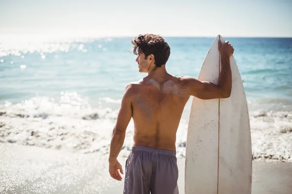 Man anläggningen surfbräda på stranden — Stockfoto