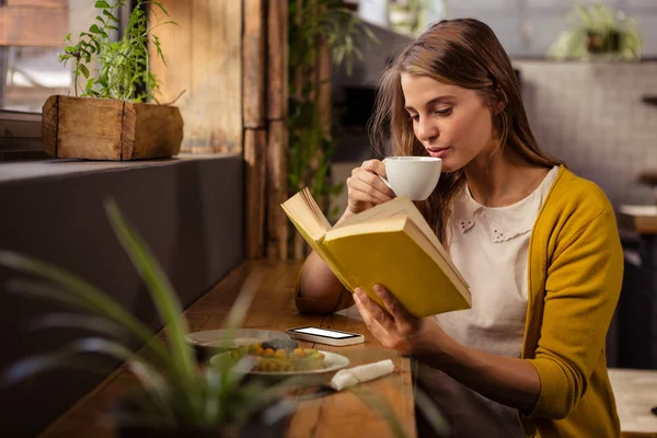 Femme lecture livre tout en buvant — Photo