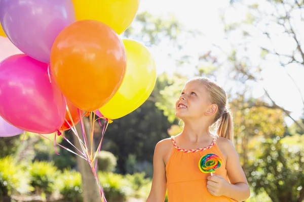 Girl holding balloons and lollypop — Stock Photo, Image