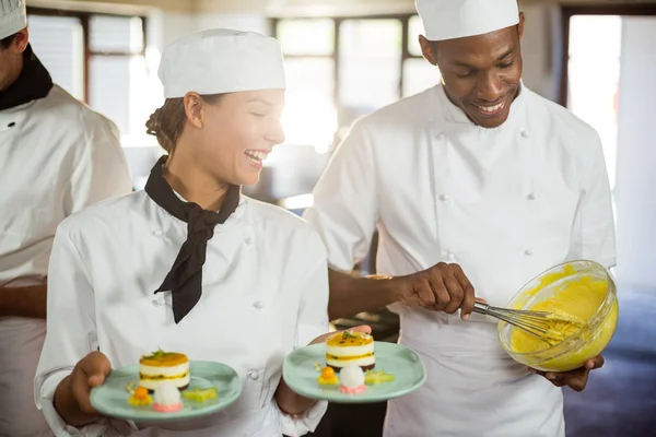 Vrouwelijke chef-kok presenteert dessert platen — Stockfoto
