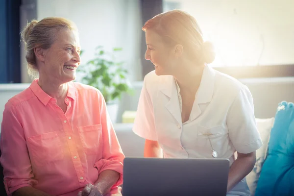 Kvinnlig sjuksköterska och senior kvinna leende medan du använder laptop — Stockfoto