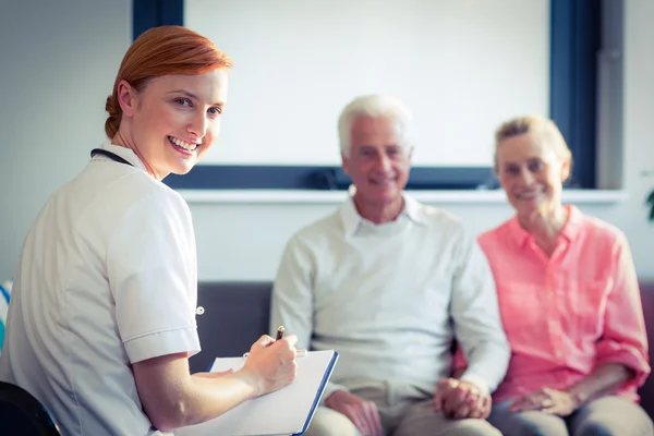 Doctor writing medical report of senior couple — Stock Photo, Image