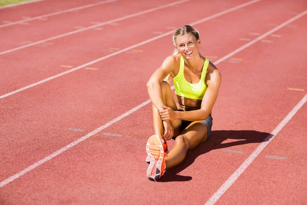 Atletka sedí na běžecké dráze — Stock fotografie