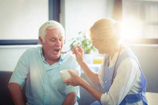 Женщина-врач кормит пожилого мужчину — стоковое фото