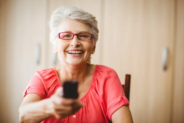 Senior mulher segurando um controle remoto — Fotografia de Stock