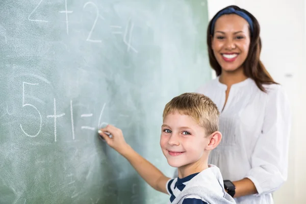 Profesor asistiendo chico en hacer adición — Foto de Stock