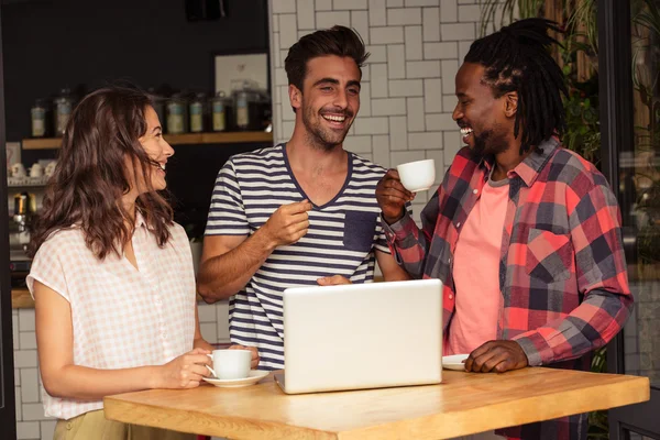 Amigos interactuando y portátil en la mesa — Foto de Stock