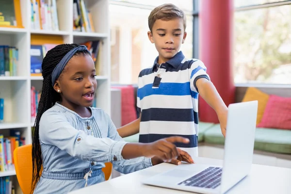 Schoolkinderen met behulp van een laptop in de bibliotheek — Stockfoto