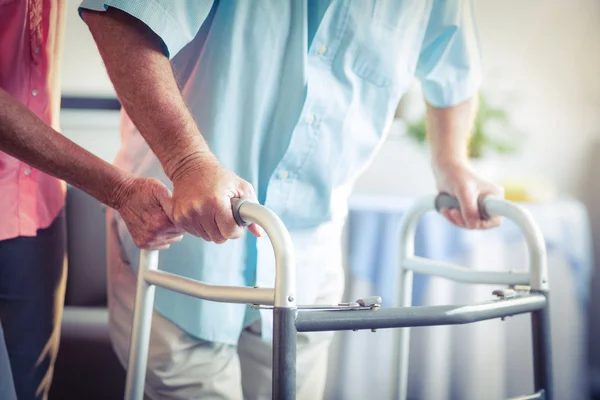 Seniorin hilft Senioren beim Gehen mit Rollator — Stockfoto