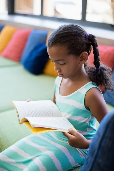 Školačka na gauči čtení knihy — Stock fotografie