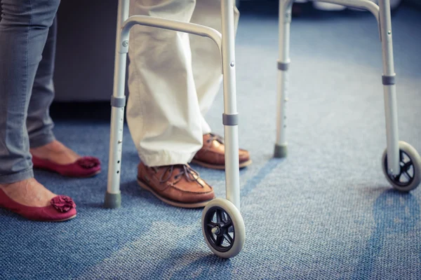 Mulher sênior ajudando o homem sênior a andar com walker — Fotografia de Stock