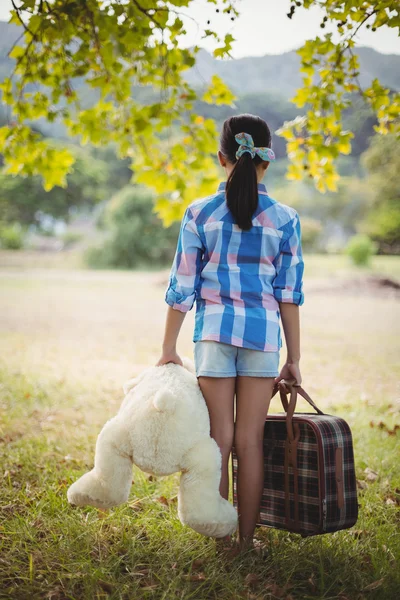 Девушка с плюшевым мишкой и чемоданами — стоковое фото