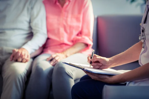 Doctor writing medical report of senior couple — Stock Photo, Image