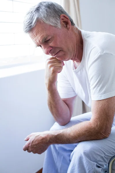 Upprörd äldre man sitter på sängen — Stockfoto