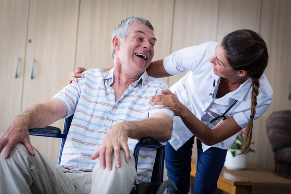 Šťastný starší muž a lékař interakce v obývacím pokoji — Stock fotografie