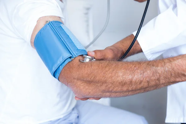 Médico verificando a pressão arterial masculina sênior — Fotografia de Stock