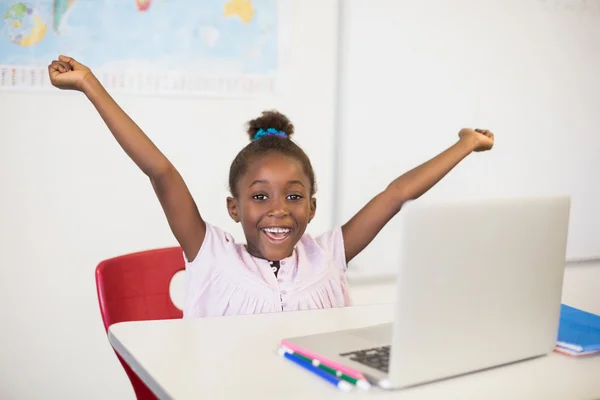 Glada skolflicka med laptop i klassrummet — Stockfoto