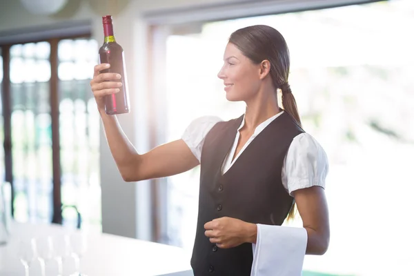 Waitress checking a wine bottle — Stock Photo, Image