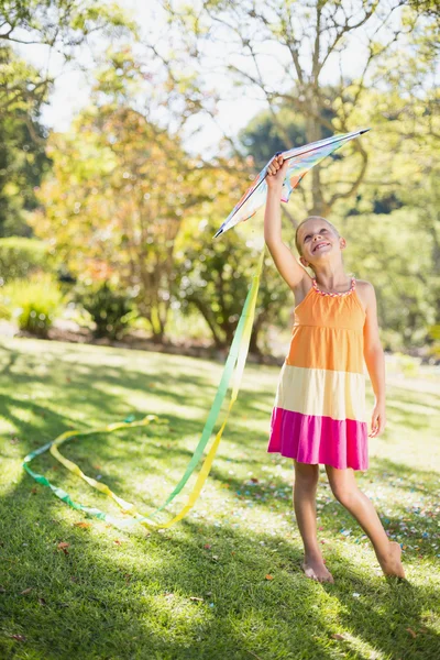 Улыбающаяся девушка держит воздушного змея в парке — стоковое фото