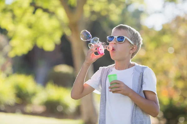 Gutt som blåser bobler gjennom boblestaven – stockfoto