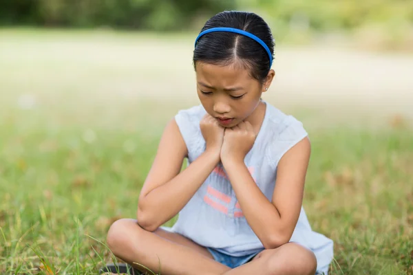 Fille bouleversée assise sur l'herbe — Photo