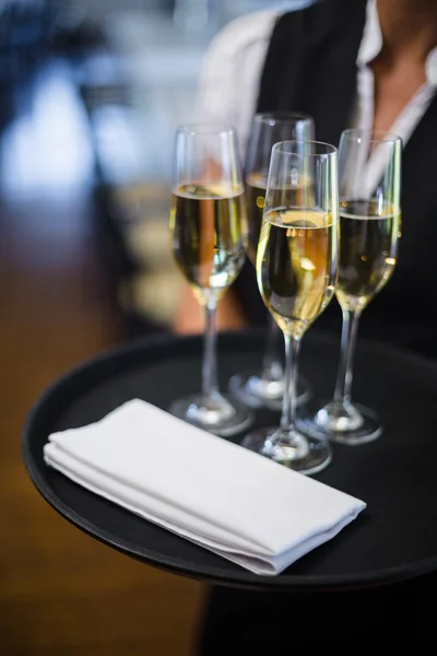 Servitrisen innehar fack med champagne flöjter — Stockfoto