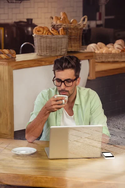 Хипстер с помощью ноутбука пьет кофе — стоковое фото