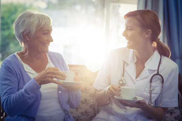 Médico sonriente y paciente hablando mientras toma el té —  Fotos de Stock