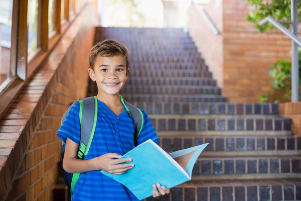 Schoolboy holding book on staircase — Stock Photo, Image