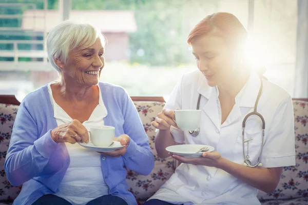 Lachende arts en patiënt met thee — Stockfoto