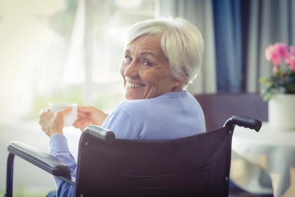 Happy senior kvinna på rullstol innehar en kopp te — Stockfoto