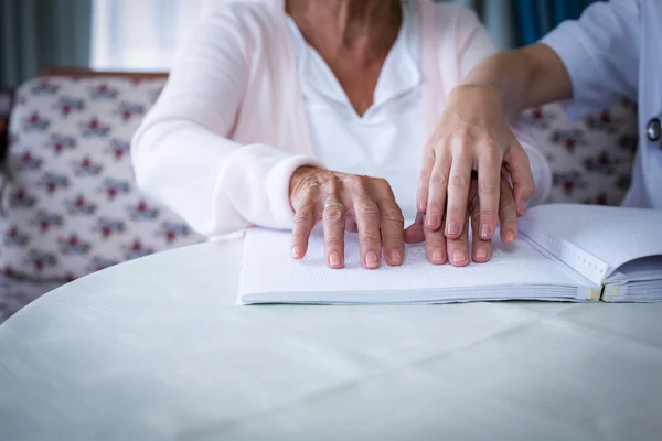 Female doctor helping a blind patient in reading — Stock Photo, Image