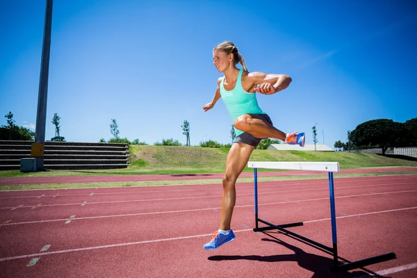 Atleta feminina pulando acima do obstáculo — Fotografia de Stock