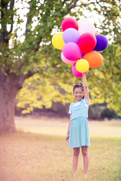 Ragazza che tiene palloncini nel parco — Foto Stock