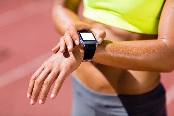 Sección media de la atleta femenina comprobando su reloj inteligente —  Fotos de Stock